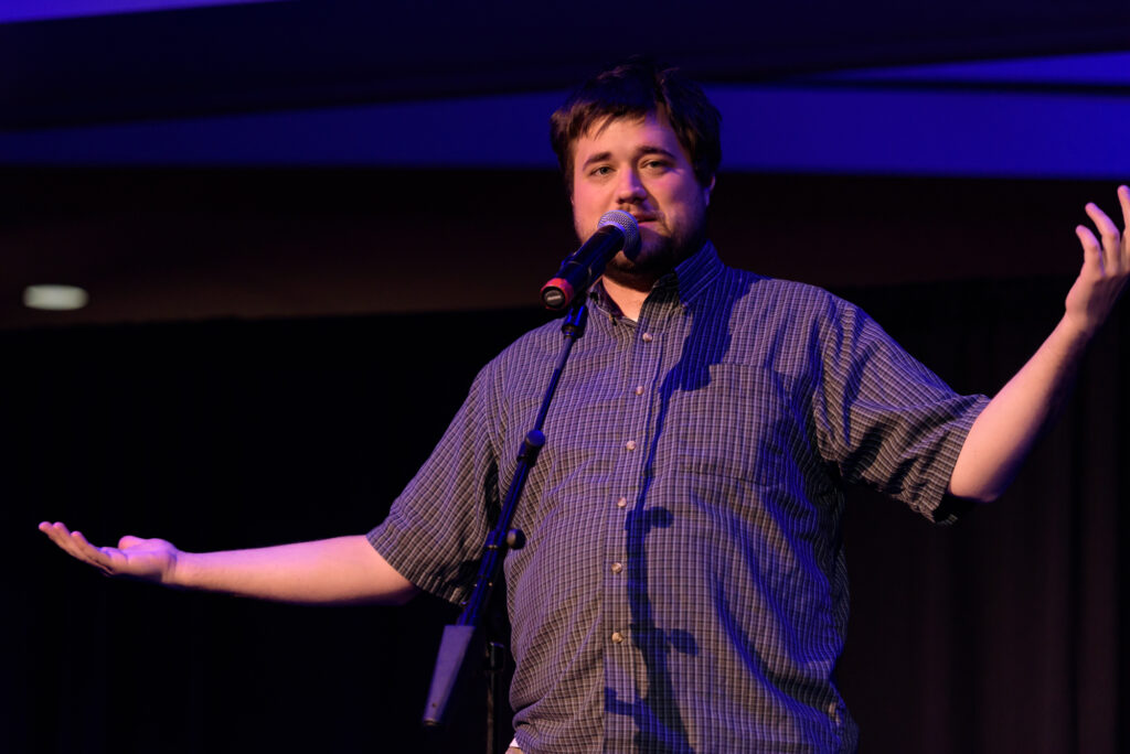 Man speaking on stage with microphone.
